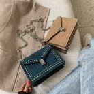 Two handbags, one blue and one beige, with studded details, on a light surface.