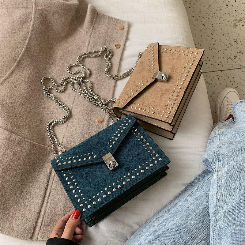 Two handbags, one blue and one beige, with studded details, on a light surface.