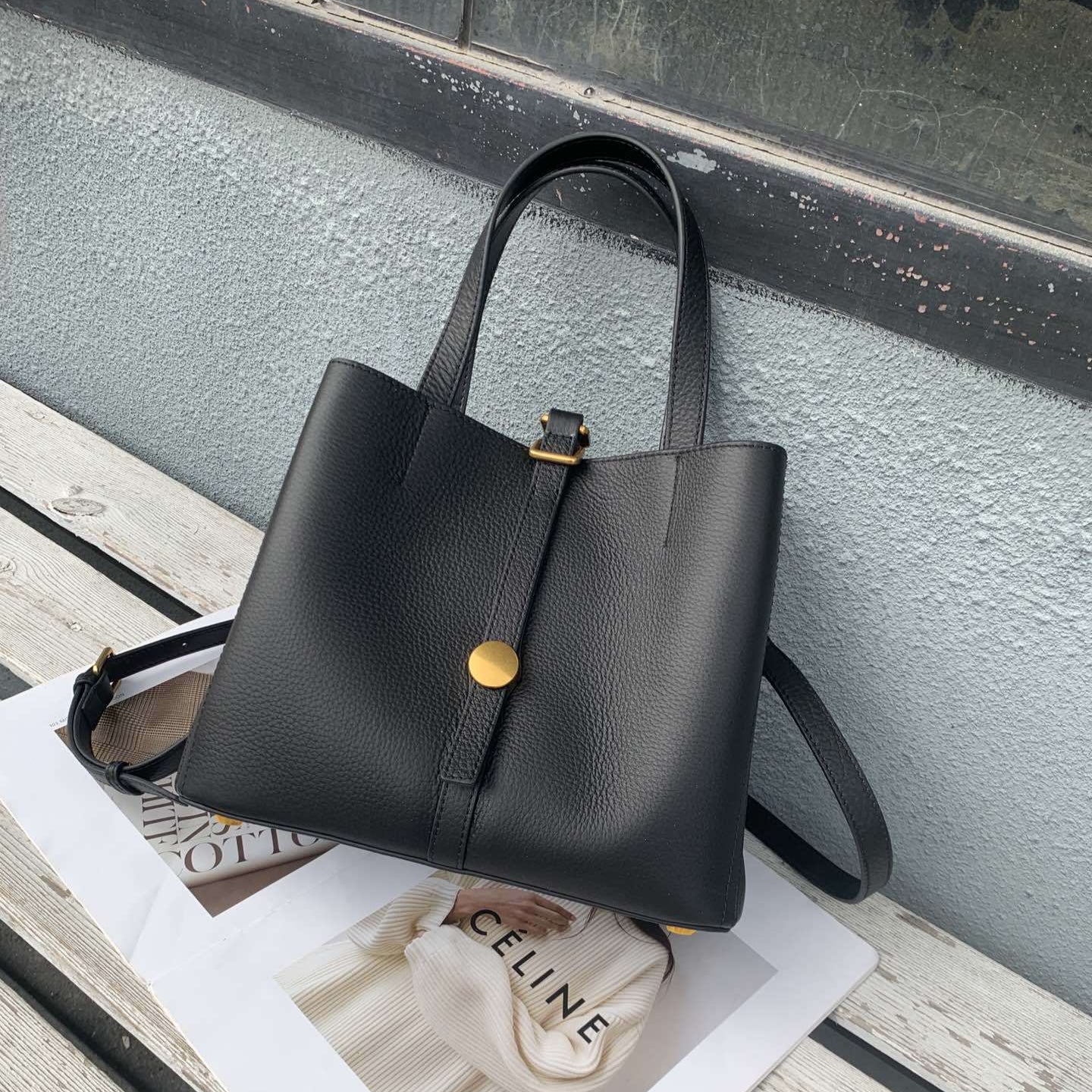 Black handbag on a magazine with a blurred background