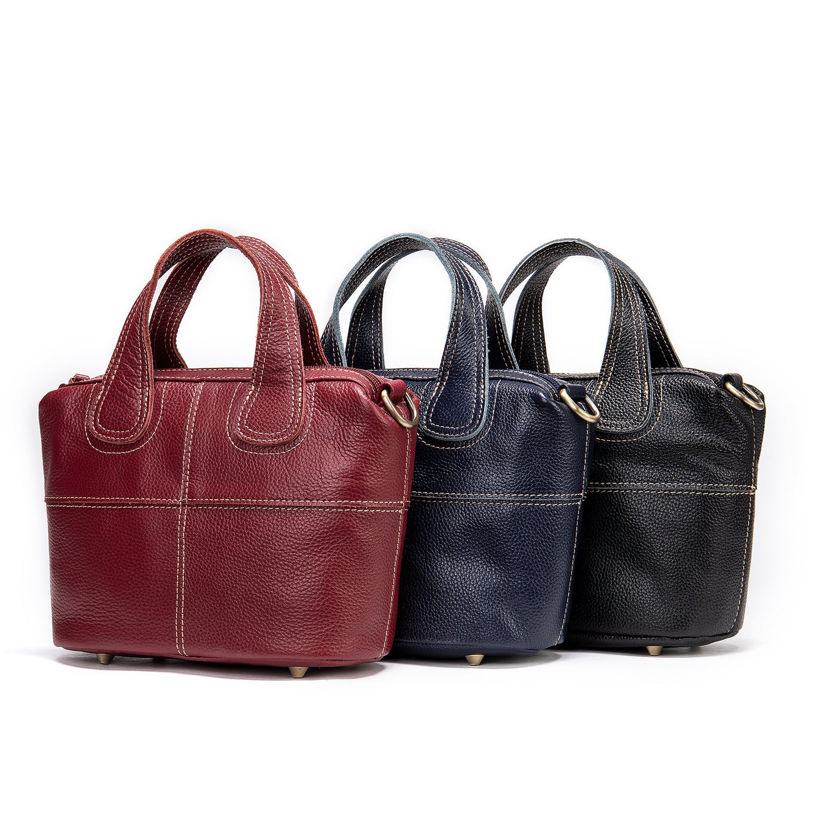 Three leather handbags in red, blue, and black on a white background