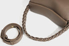 Brown leather handbag with braided strap on a white background