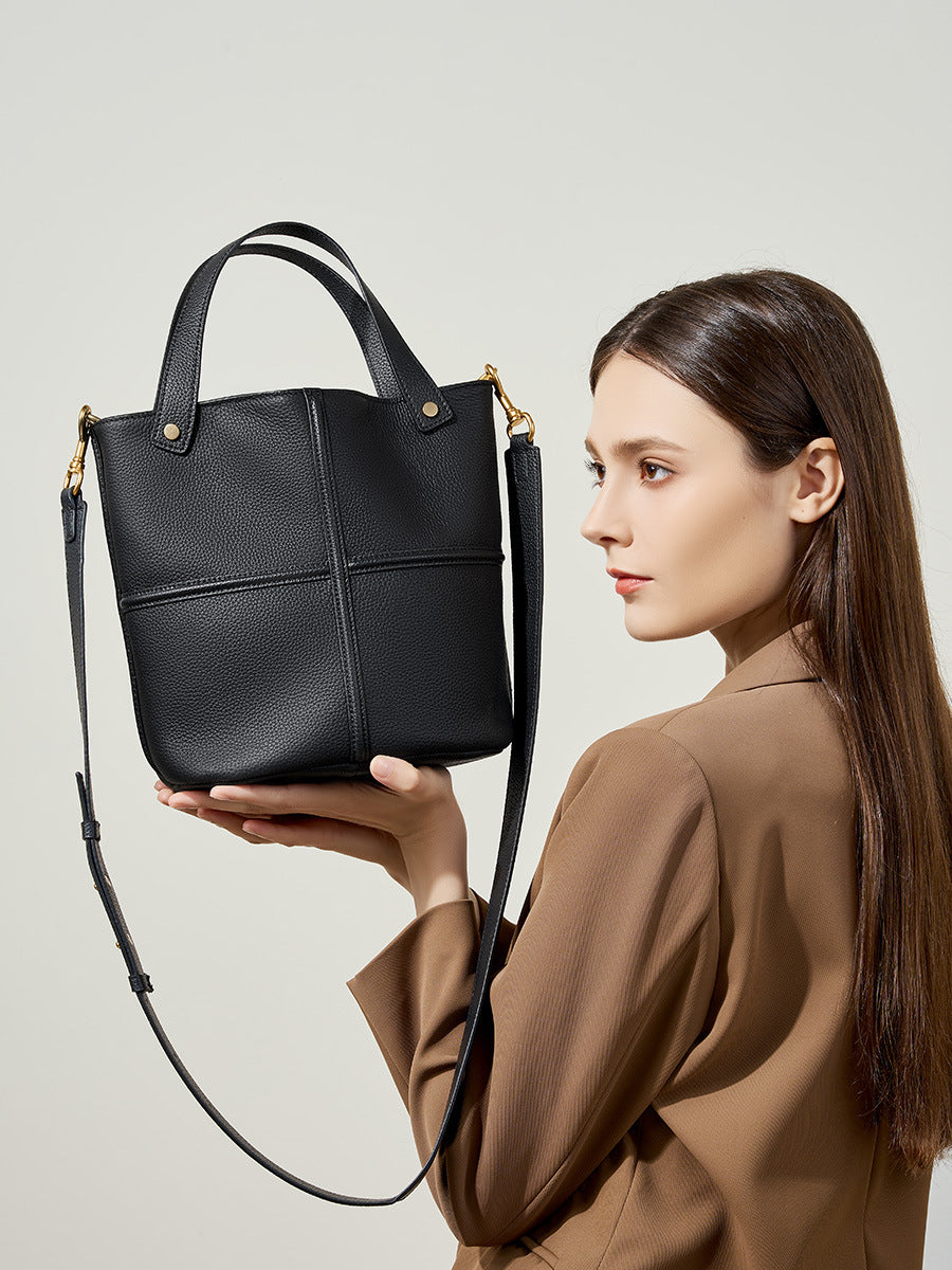 Woman holding a black handbag against a neutral background