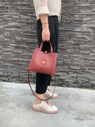 Person holding a pink handbag against a stone wall background
