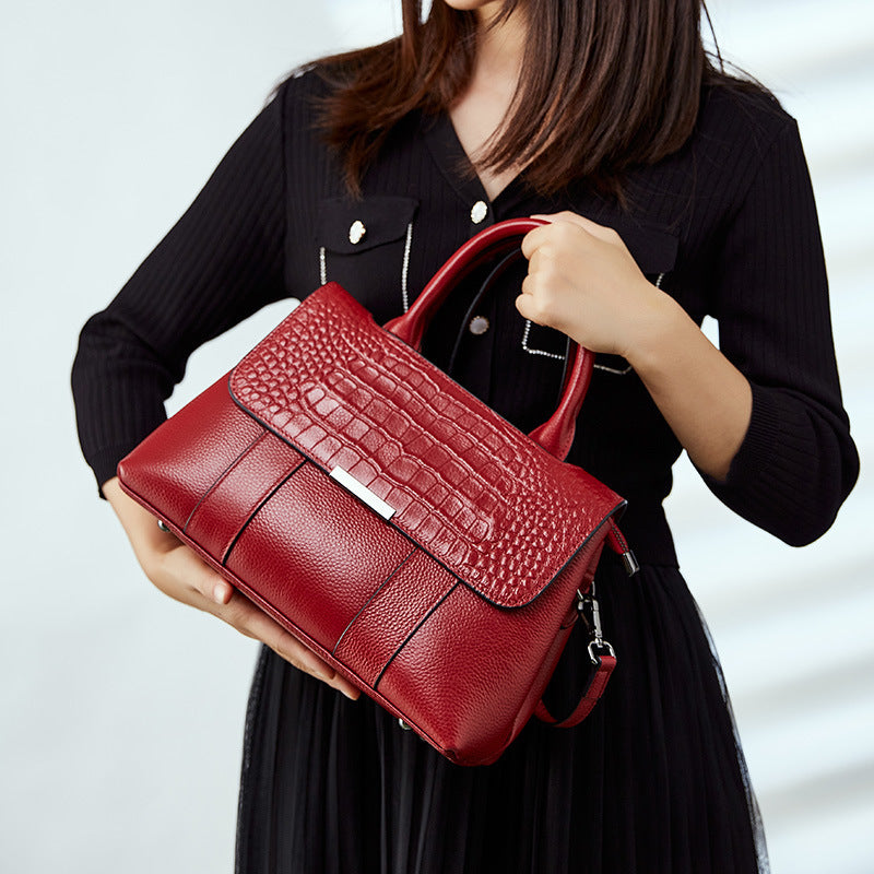 Red textured handbag held by a person against a neutral background