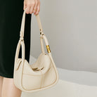 Beige handbag held by a person against a neutral background