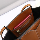 Brown leather handbag with a red pen inside on a white background