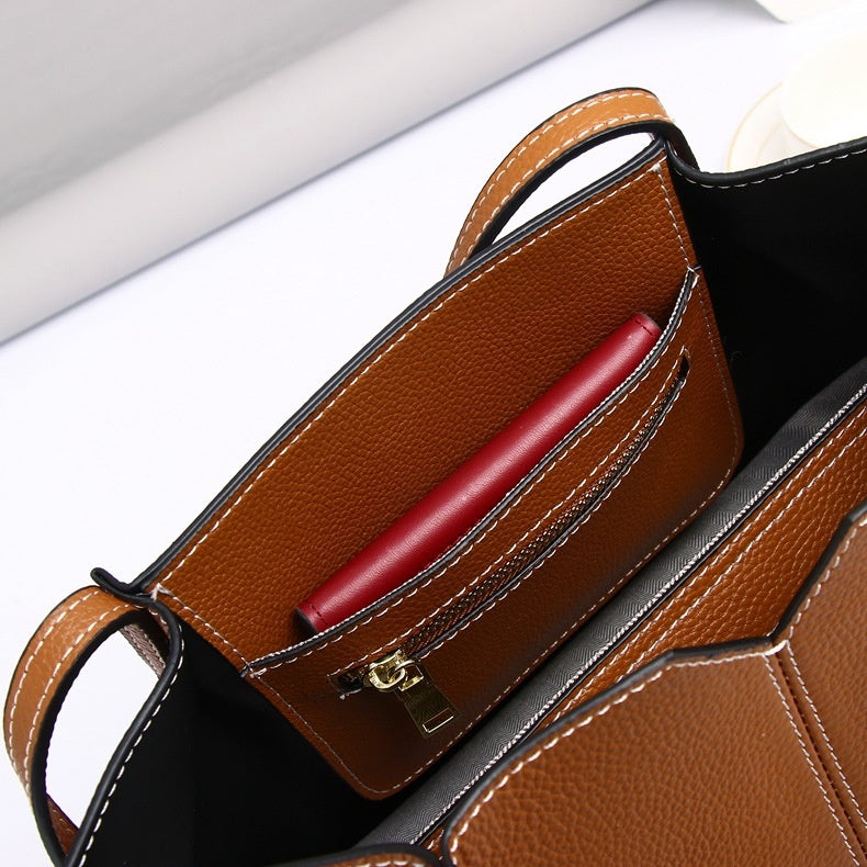 Brown leather handbag with a red pen inside on a white background