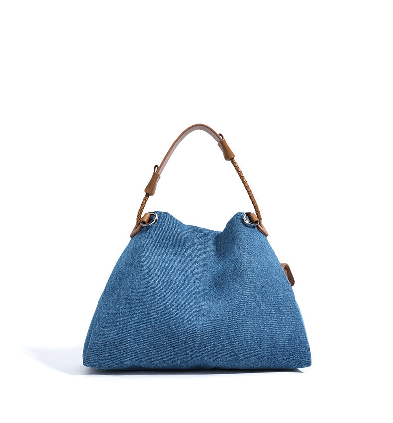 Blue Denim handbag with brown leather handle on a white background