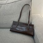 Brown leather handbag on a gray sofa