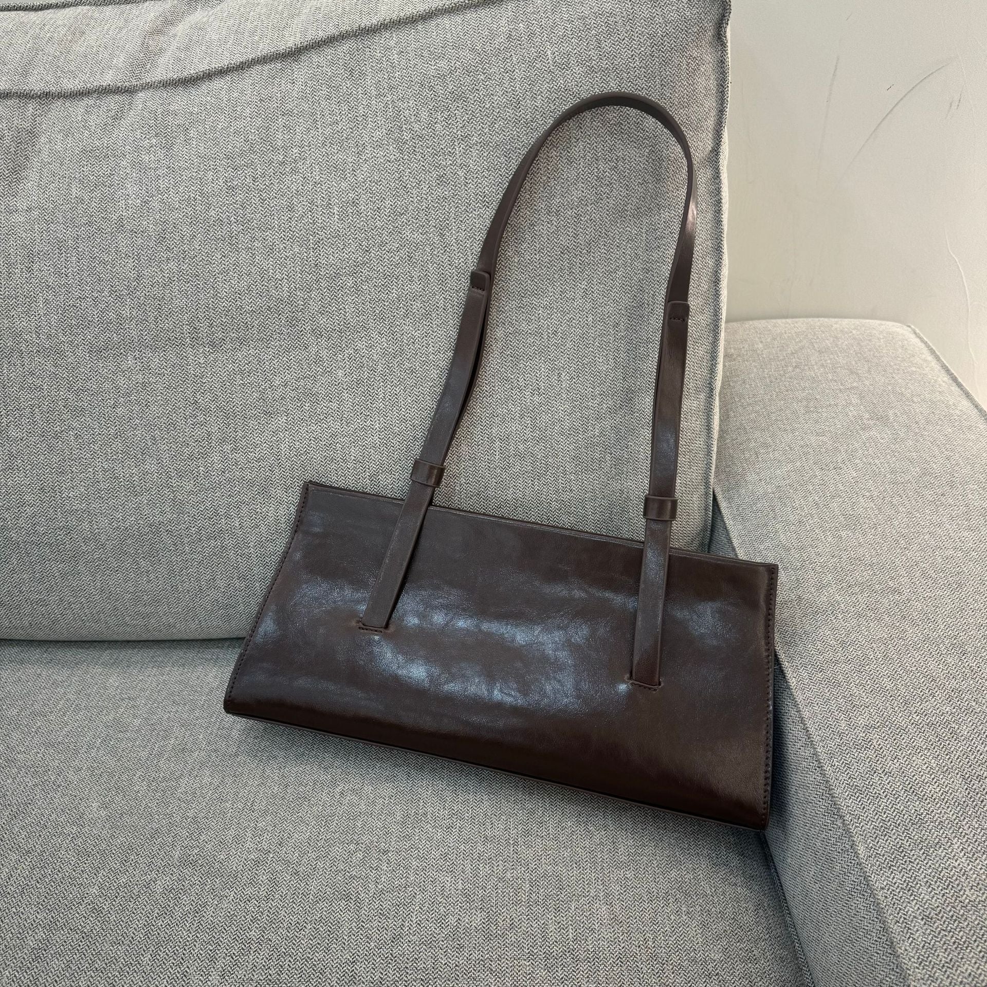 Brown leather handbag on a gray sofa