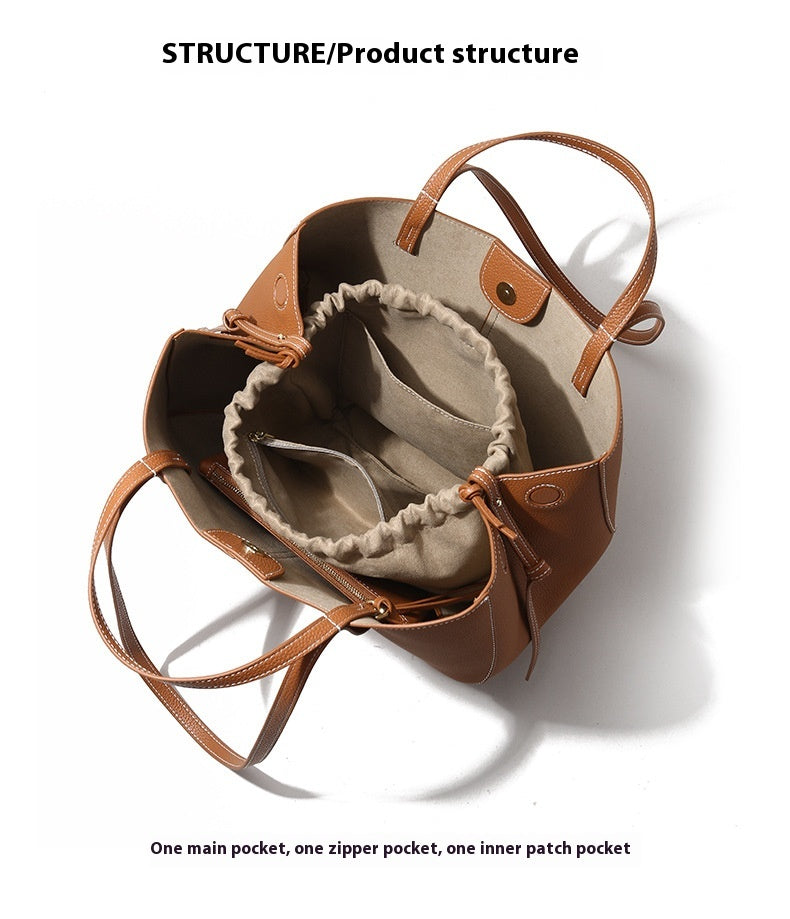 Brown leather handbag with beige interior on a white background