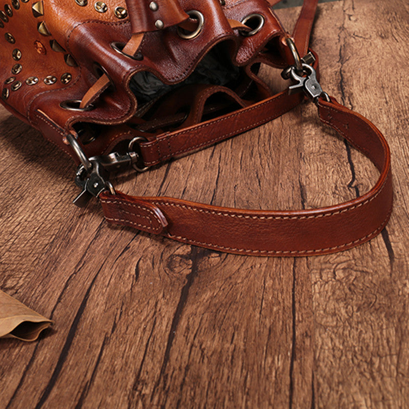 Brown leather bag with studs on a wooden surface