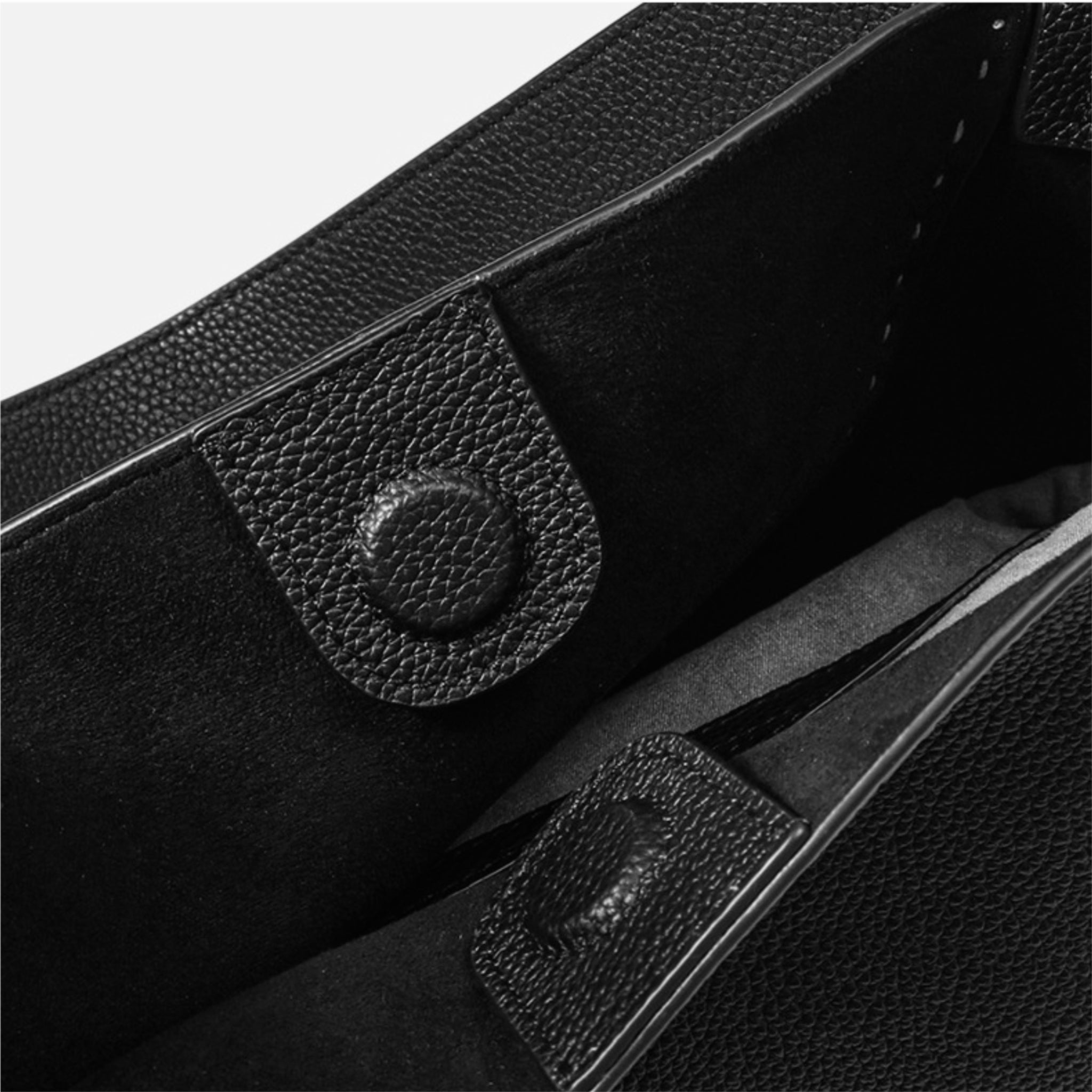 Close-up of a black leather bag with a flap and strap.