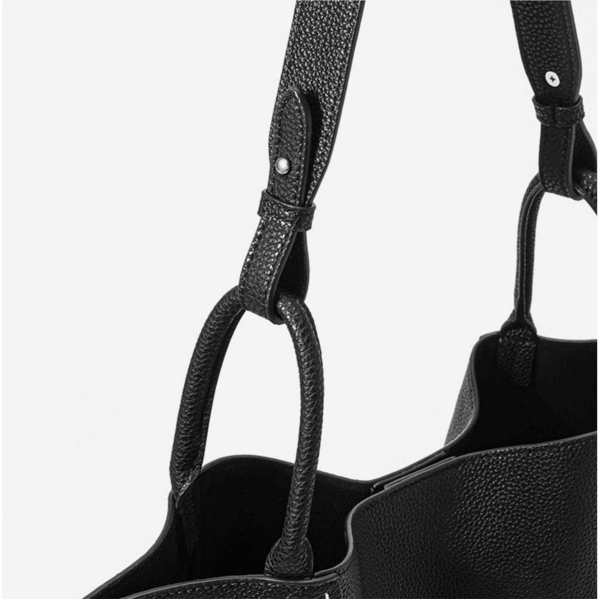 Close-up of a black leather handbag with a strap on a light gray background