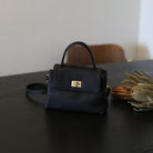 Black handbag on a dark surface with a blurred background