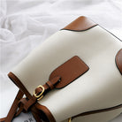 White handbag with brown leather accents on a white background