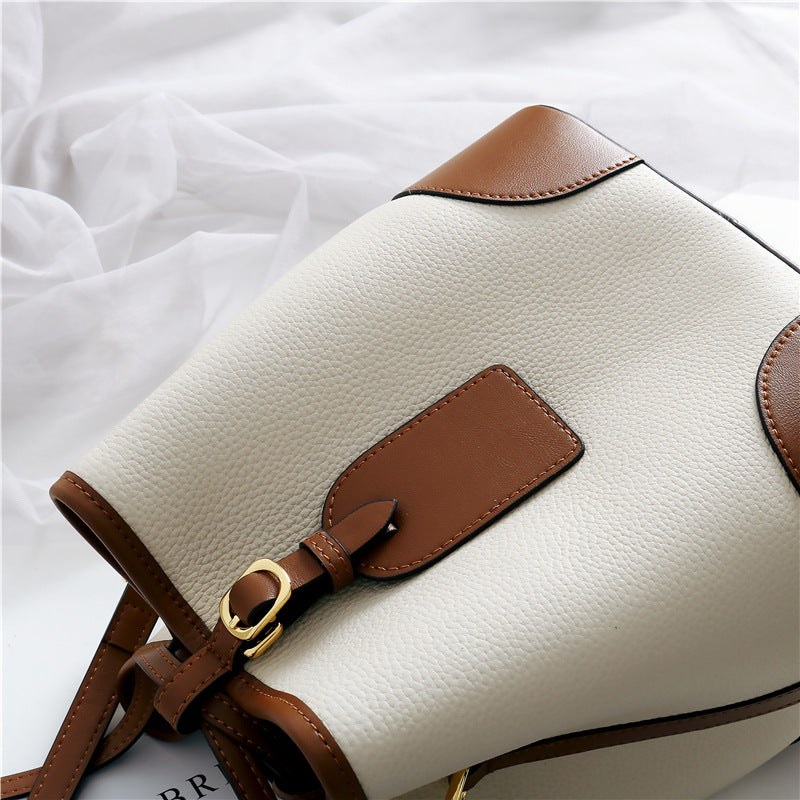 White handbag with brown leather accents on a white background