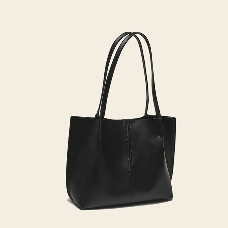 Black leather tote bag on a beige background