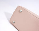 Close-up of a light pink wallet with silver rivets on a white background
