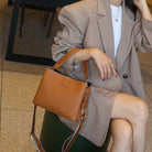 Person holding a brown handbag in an indoor setting