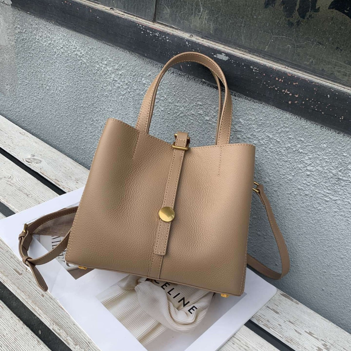Beige handbag with gold accents on a surface with a blurred background