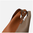Brown leather handbag with a strap on a light gray background