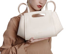 White handbag held by a person against a white background