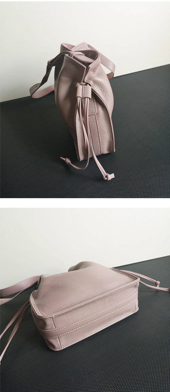 Pink leather bag on a black surface with a white background