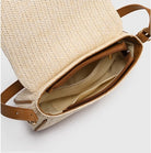 Beige woven handbag with brown leather straps on a light gray background