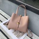 Pink handbag on a wooden surface with a magazine underneath