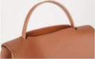 Brown leather handbag with a handle on a light gray background
