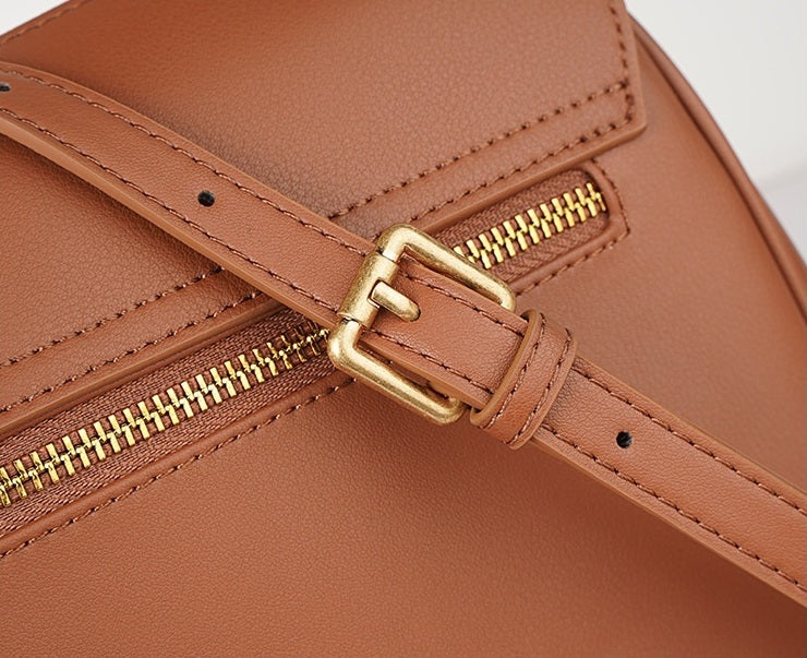 Brown leather bag with gold zipper and buckle on a light gray background