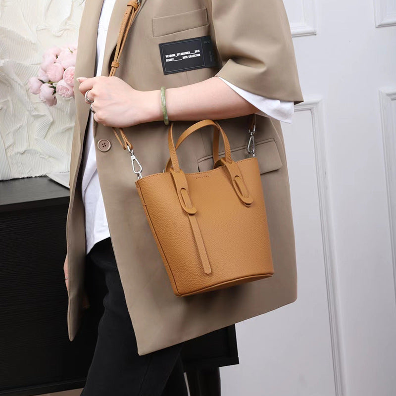 Person holding a tan handbag with a neutral background