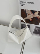 White handbag on a stand with a magazine in the background