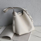 White handbag on top of an open book with a gray wall background