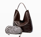 Brown leather handbag and gray drawstring pouch on a white background