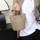 Person holding a beige handbag with a blurred background