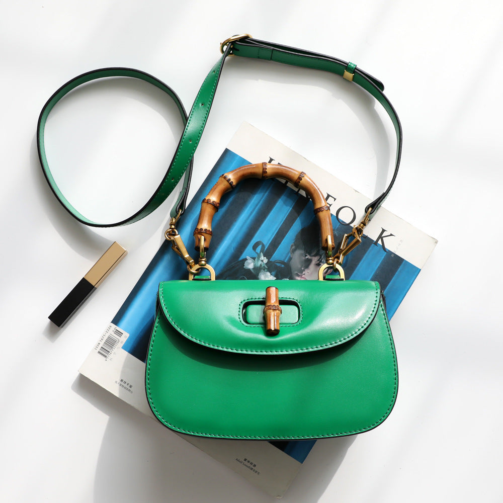 Green handbag with wooden handle on top of a magazine