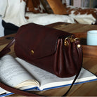 Brown leather handbag on an open book with a blurred background