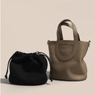 Black drawstring bag and beige handbag on a beige background