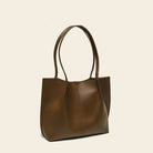 Brown leather tote bag on a beige background