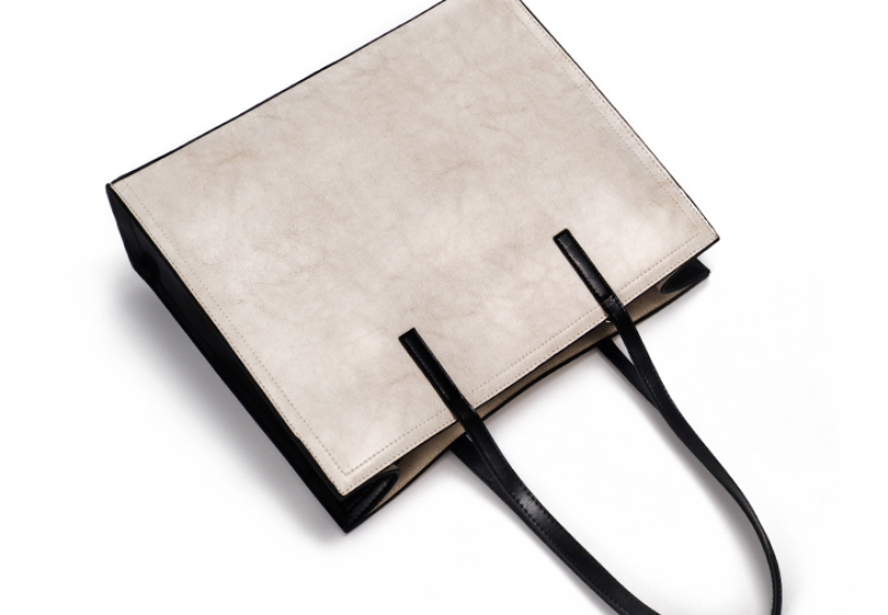 Beige tote bag with black handles on a white background