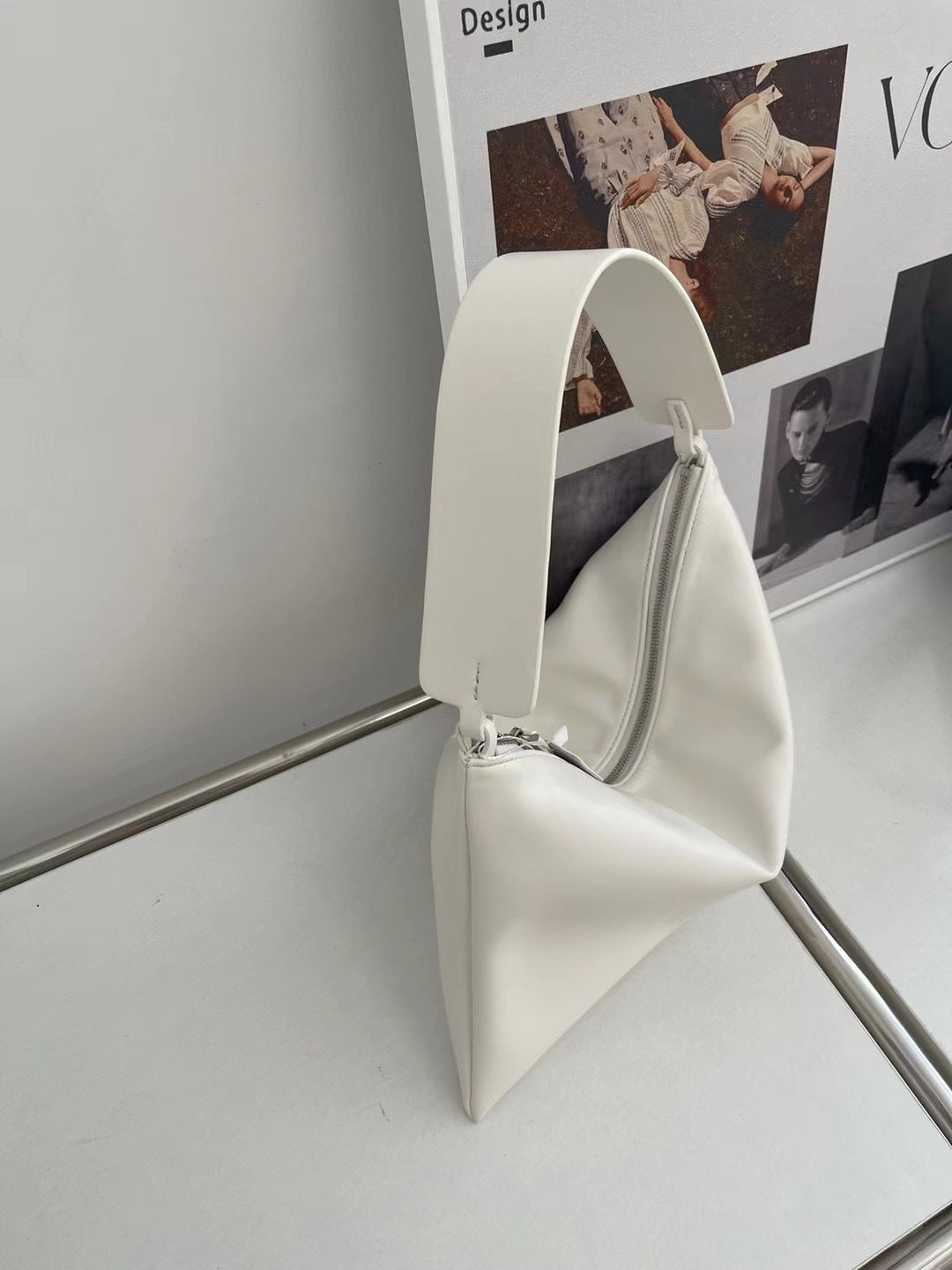 White handbag on a stand against a light gray background