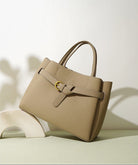 Beige handbag with a gold buckle on a light background