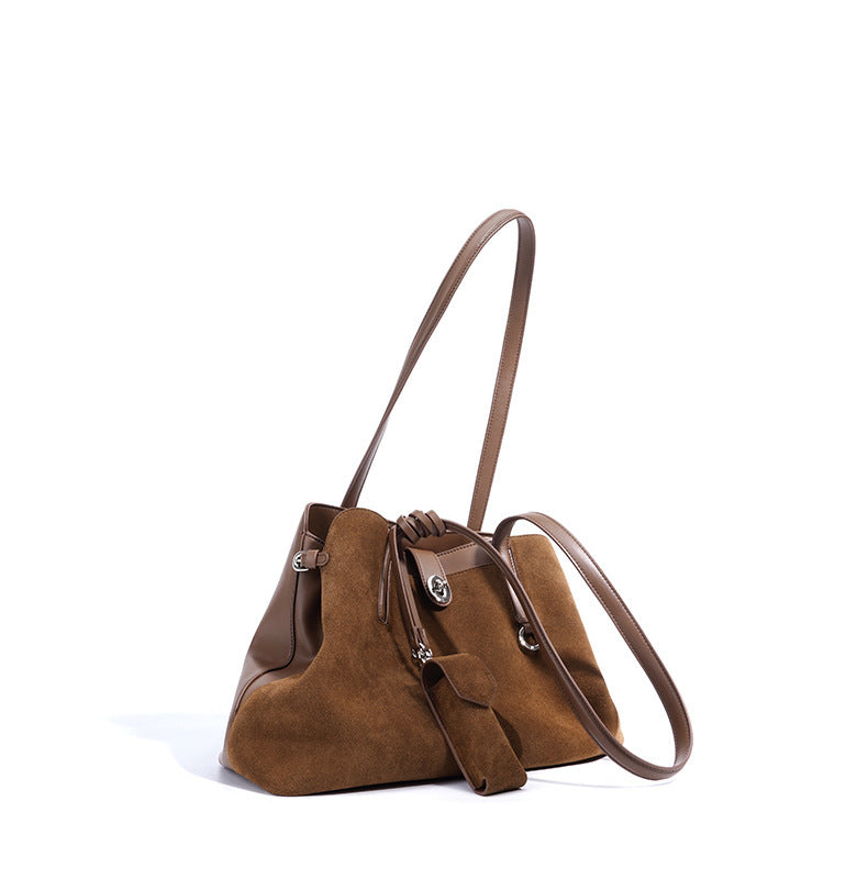 Brown suede handbag with a matching strap on a white background
