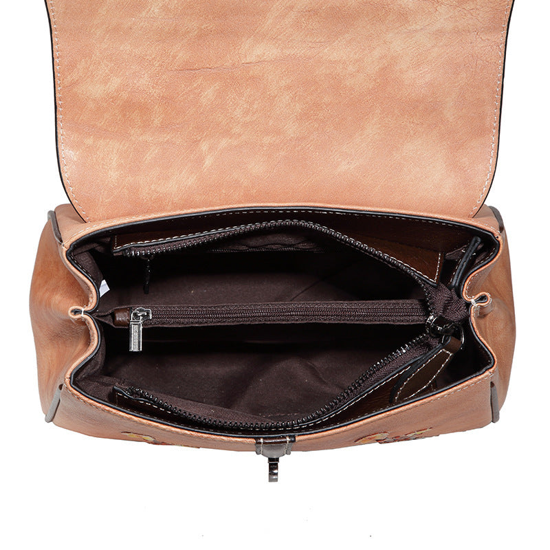 Brown leather bag with open interior on a white background