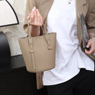 Person holding a beige handbag with a blurred background