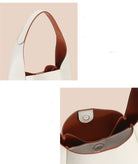 Close-up of a handbag with brown interior and beige exterior, featuring a shoulder strap.