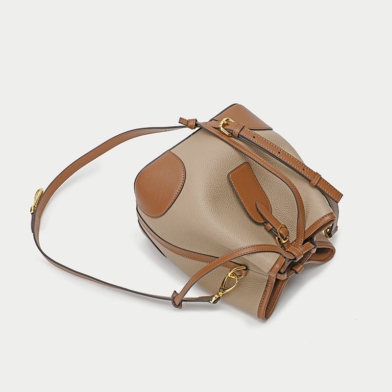 Beige and brown leather handbag with gold hardware on a light gray background