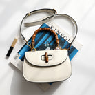 White handbag with wooden handle on top of a magazine
